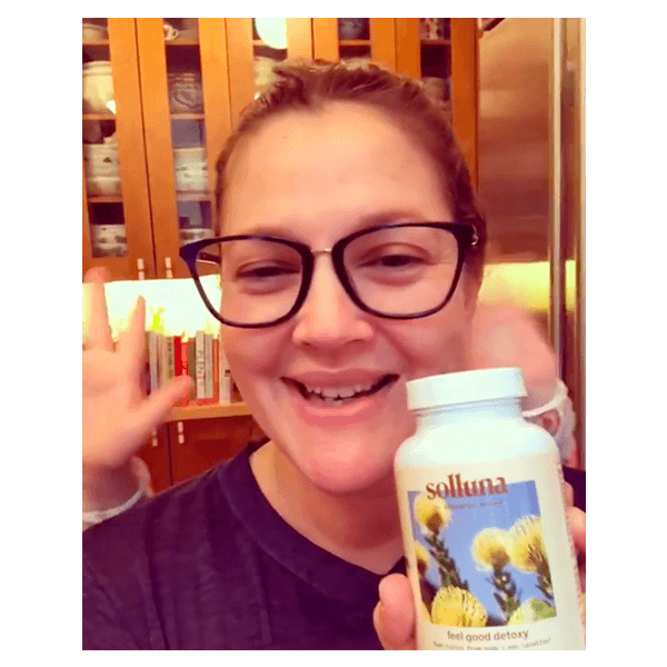 Drew Barrymore holds up a bottle of Solluna's Feel Good Detoxy 2.0