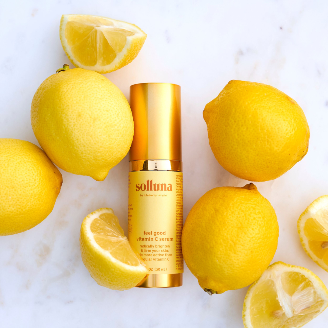 A bottle of Feel Good Vitamin C Serum surrounded by lemons.