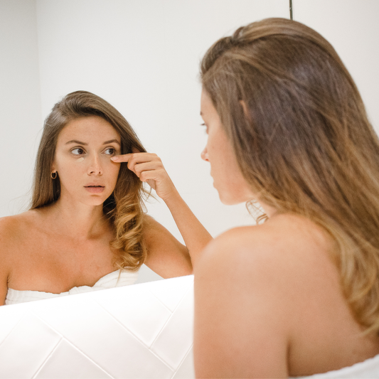 A woman covering her dark circles under her eyes with make-up.