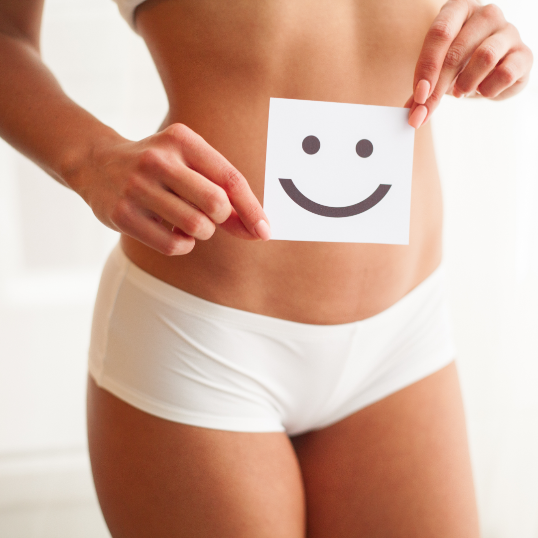 A woman with good digestion holding a happy face over her stomach.