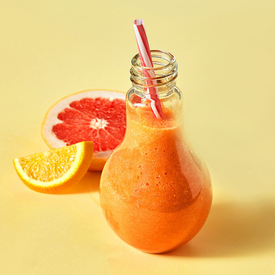 Orange smoothies with citrus, carrots, sea buckthorn and almonds on an orange paper background