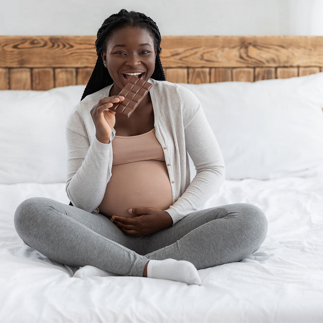 Happy pregnant woman eating cake at home