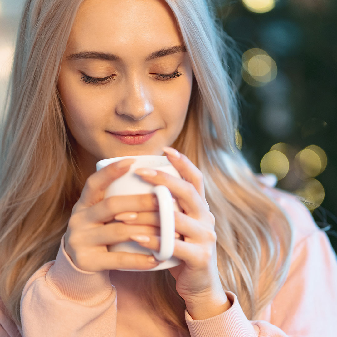 Pretty young woman enjoying a warm holiday drink