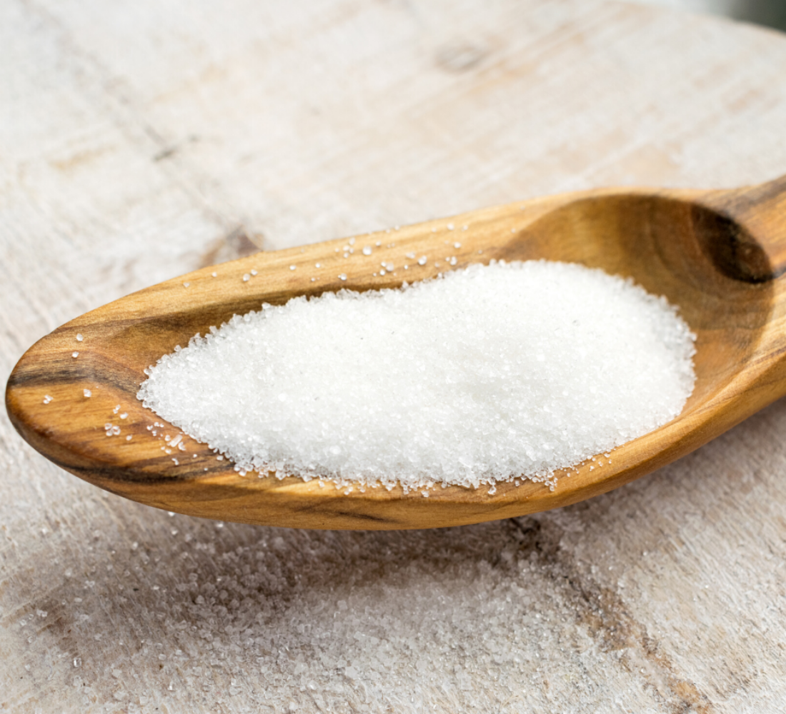 Sugar granules in wooden spoon
