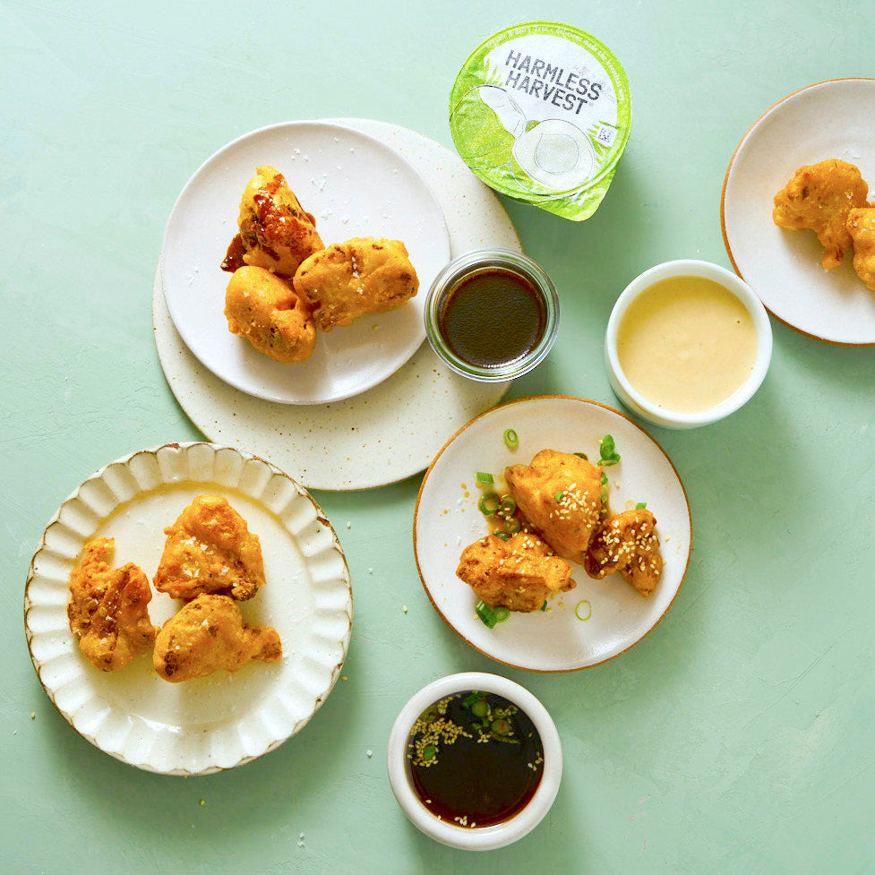 Cauliflower bites arranged on table with three different sauces.