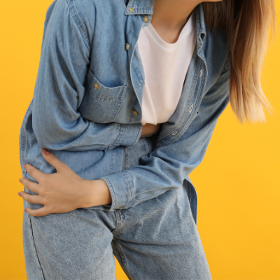 Young woman with an unhealthy gut clutching her stomach from abdominal pain.
