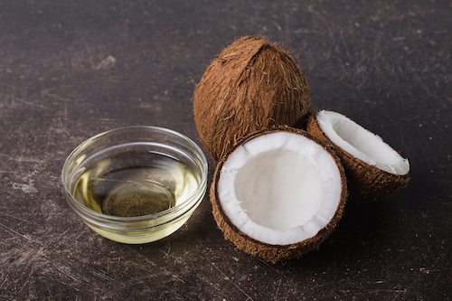 Coconut and coconut oil on a dark marble background. Exotic large walnut. Personal care. Spa treatments. Coconut concept.