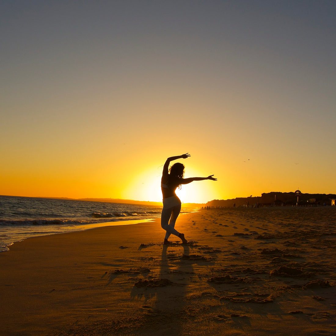 Kimberly Snyder practicing yoga on the beach at sunset.