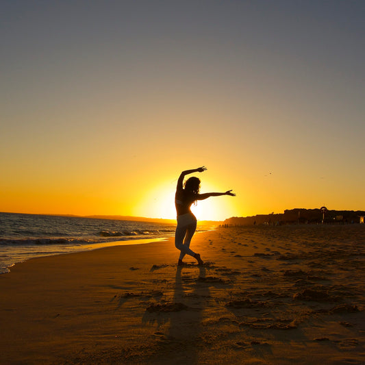 Kimberly Snyder practicing yoga on the beach at sunset.