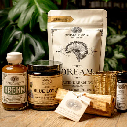 Anima Mundi product set including a bag, bottles, and containers on a wooden surface with green foliage in the background.