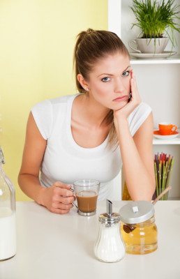 Picture of a woman with a cup of coffee and sugar and honey in front of her