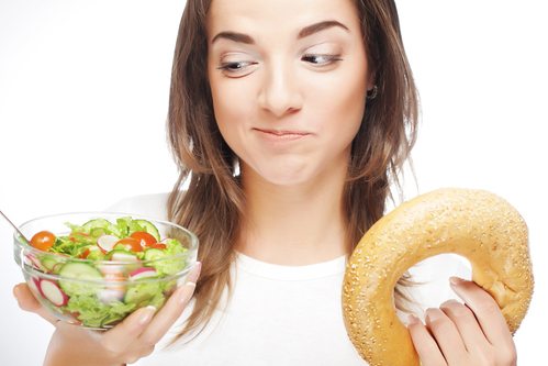 Female holding a salad vs a bagel