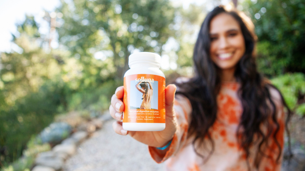 Kimberly Snyder holding Feel Good Digestive Enzyme supplements.