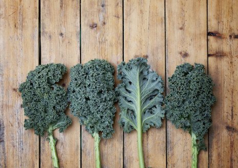 Picture of four pieces of kale on top of a wooden table