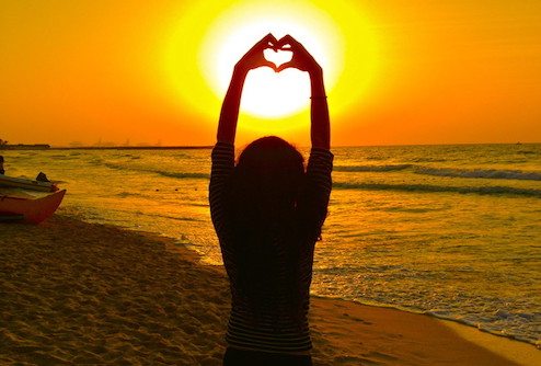 Picture of female on beach making heart shape with hands