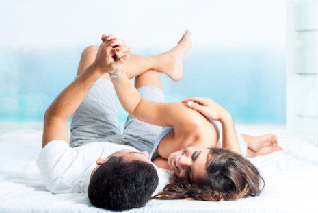 Picture of couple laying down smiling and holding hands