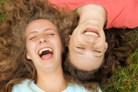 Picture of young girls laying down on grass, laughing