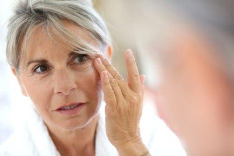 Picture of mature woman looking at wrinkles around her eyes