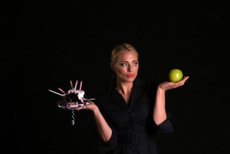 Picture of female holding cake in one hand and an apple in the other
