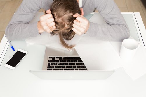 Picture of stressed man leaning over computer and phone