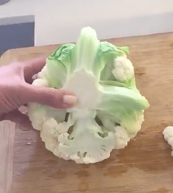 Picture of Kimberly's hand holding a cauliflower on a cutting board