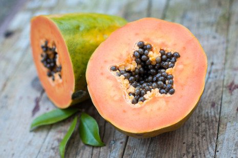 Picture of two halves of tropical papaya fruit on wood