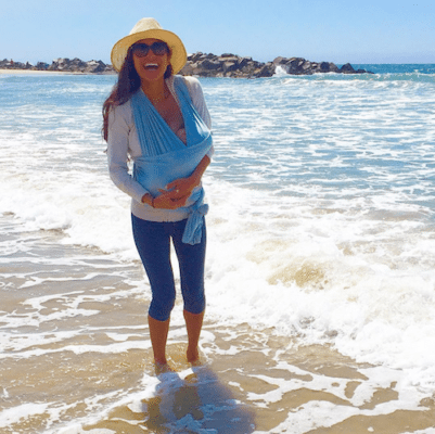 Picture of Kimberly wearing a big hat on the beach with Lil Bub. 