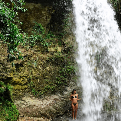 Kimberly standing under a waterfall. 