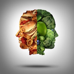 Food concept and diet decision symbol or nutrition choice dilemma between healthy good fresh fruit and vegetables or greasy cholesterol rich fast food as a human head with two conflicting sides trying to decide what to eat.