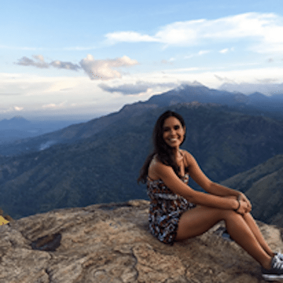 Picture of Kimberly sitting on top of a large mountain top. 