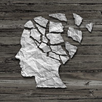 Mental health care concept as a sheet of torn crumpled white paper shaped as a side profile of a human face on an old grungy wood background as a symbol for neurology and dementia issues or memory loss.