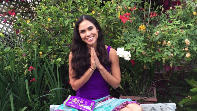 Kimberly sitting outside with hands together in a namaste gesture. 
