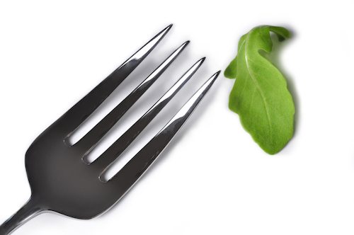 A fork next to a rucola leaf to illustrate the concept of diets.