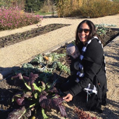 Picture of Kimberly Snyder bending down and choosing veggies from a farm. 