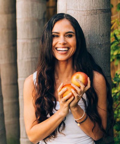 Picture of Kimberly standing outside holding some fresh apples. 