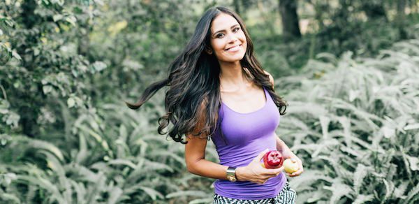 Kimberly smiling while holding an apple outdoors. 