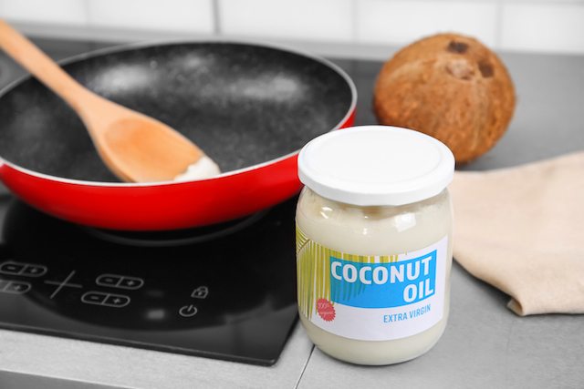 Coconut oil in glass jar and frying pan on background