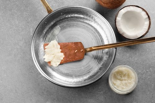 Spatula with coconut oil in frying pan on table