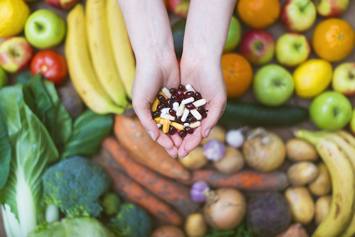 Woman hands holding natural medicine or supplements on a fruit and vegetables background