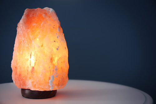 Himalayan salt lamp on table against color background