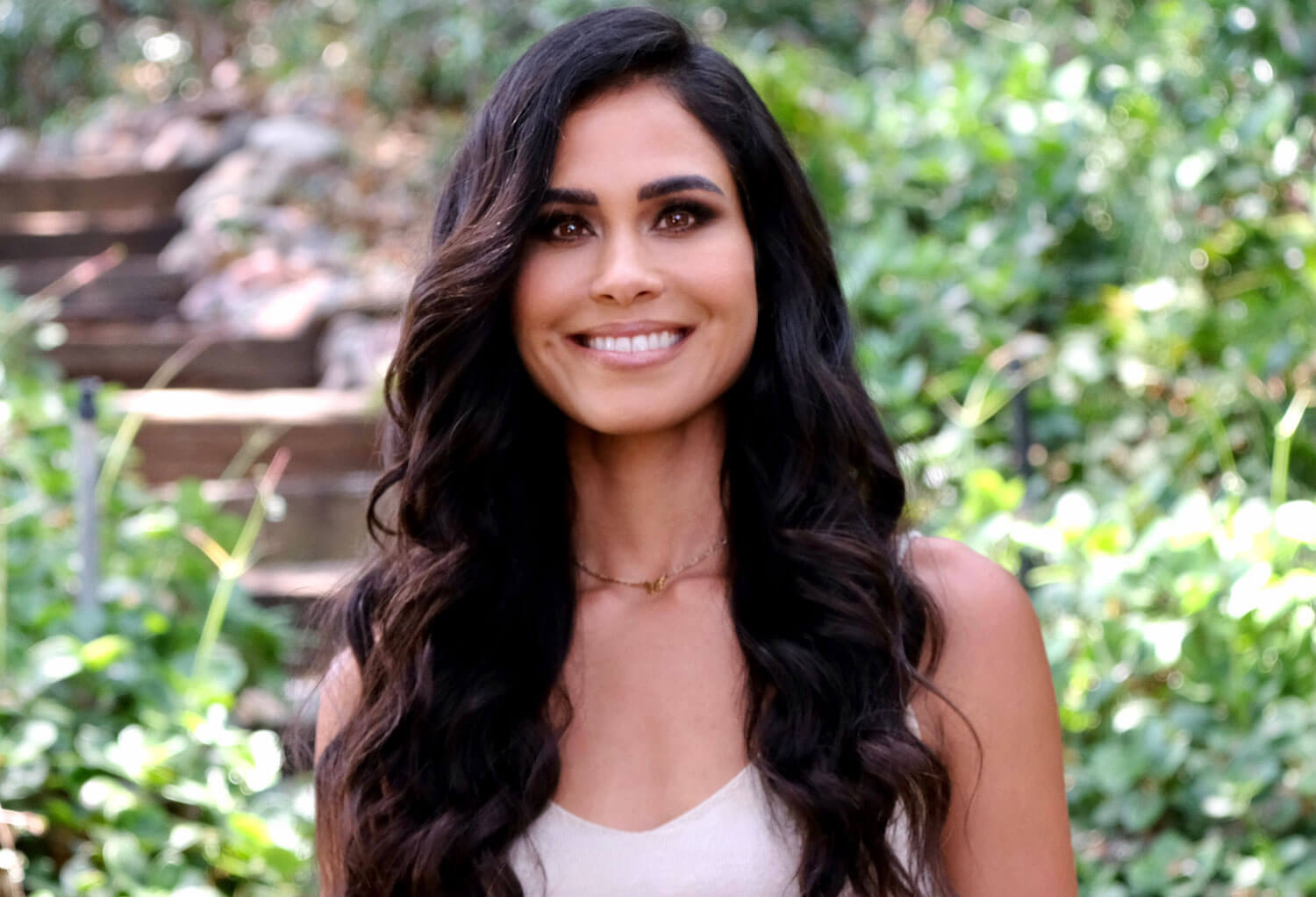 Kimberly Snyder Headshot smiling with steps greenery in background