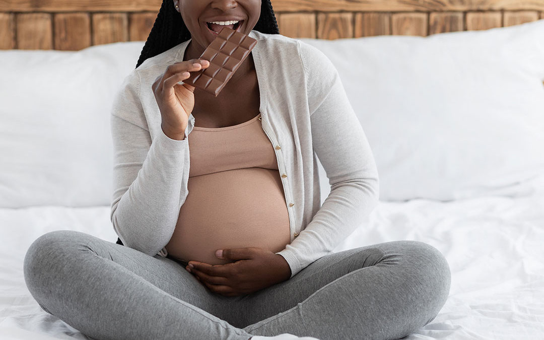 Happy pregnant woman eating cake at home