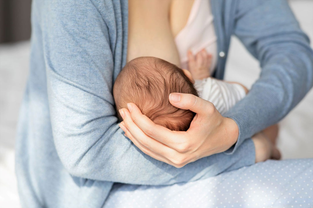 Breastfeeding mother cradles her baby's head to make sure he's properly latched