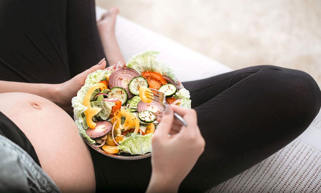 Young pregnant woman eating a vegetable salad