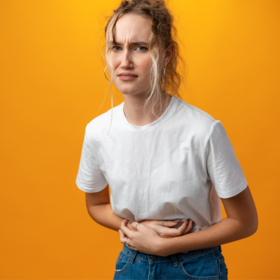 Uncomfortable young woman clutching her stomach from gas and discomfort from an unhealthy gut.