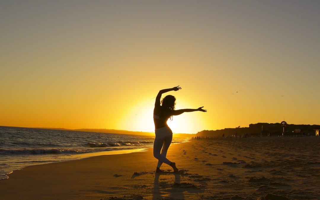 Kimberly Snyder practicing yoga on the beach at sunset.