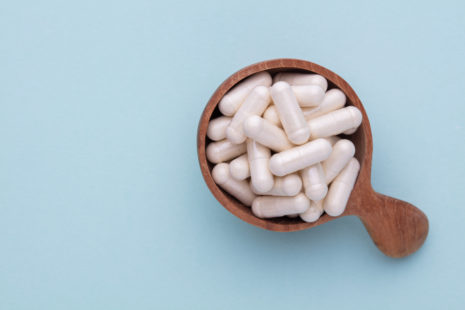 Plant-based capsules in a cup on a blue background.