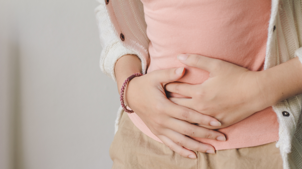 A woman with uncomfortable bloating holding her stomach.
